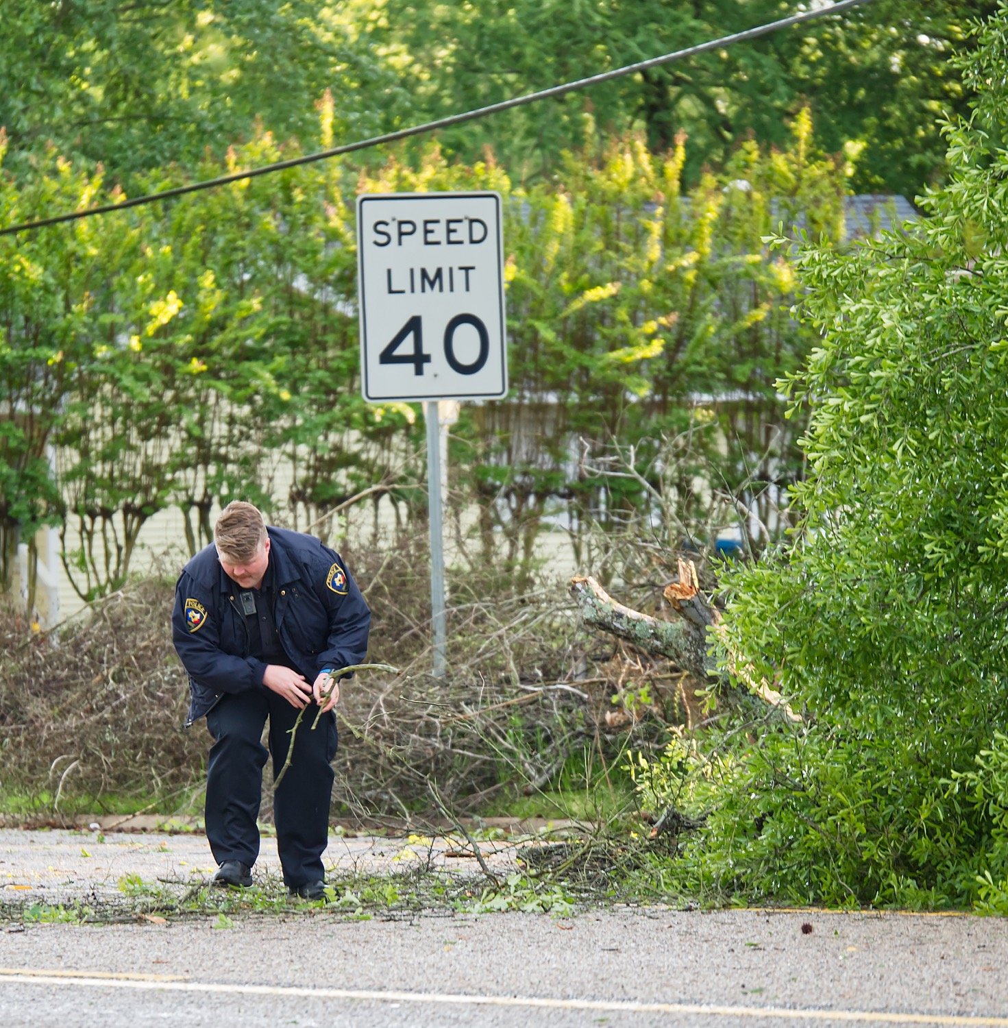A Mineola policeman helps clear debris from Pacific Ave./U.S. Hwy. 69 Sunday after the second storm passed.